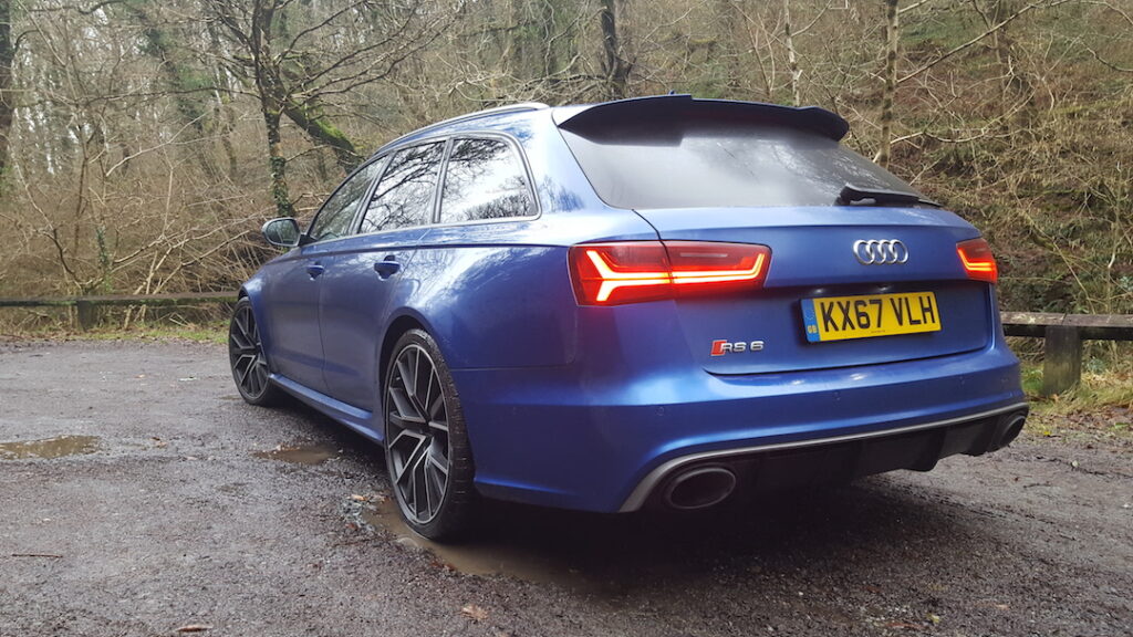 Rear view of a blue Audi RS6 parked outside with brake lights on