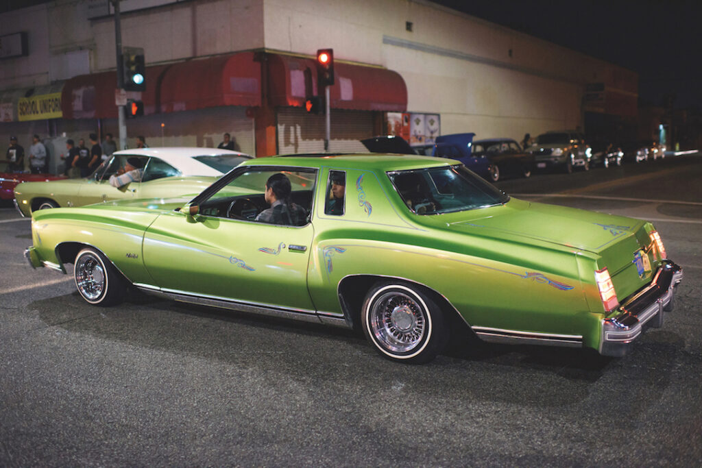 A green lowrider moves down the street.