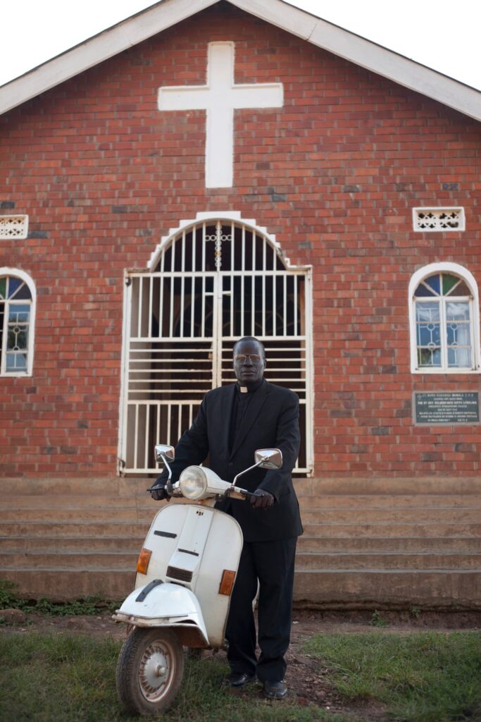 A reverend outside his place of worship - with his Vespa