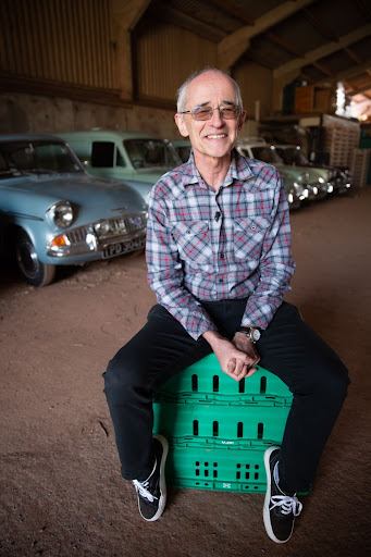 Auboné Braddon sitting on a green crate in front of some of his cars